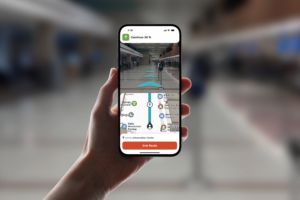 A passenger standing in the Blue Grass Airport lobby with a phone in their hand using the GoodMaps app.