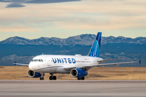 A United Airlines Airbus A-319 on a tarmac, with mountains in the background.