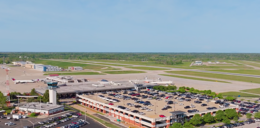 An aerial view of Blue Grass Airport on a clear day. The view shows the parking garage, the terminal and the runway.