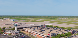 An aerial view of Blue Grass Airport on a clear day. The view shows the parking garage, the terminal and the runway.