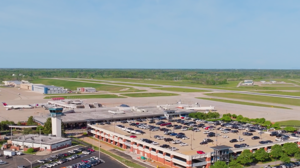 An aerial view of Blue Grass Airport on a clear day. The view shows the parking garage, the terminal and the runway.