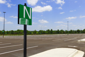 A parking row sign in front of a large open parking lot on a sunny day.