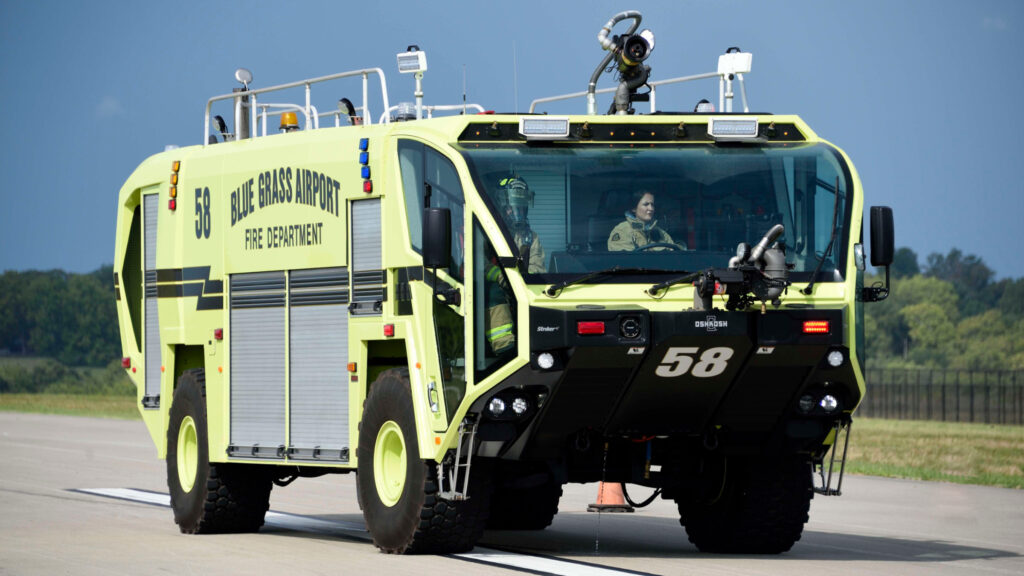 A green aircraft rescue firefighting truck on the runway.